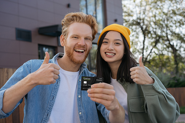 Friends smiling in camera while holding a credit card
